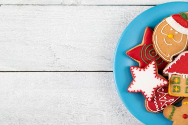 Beyaz ahşap arka planda güzel dekore edilmiş bir tabak Noel kurabiyesi. Kurabiyelere odaklan