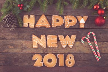 Güzel dekore edilmiş Noel kurabiyelerinin masa başı fotoğrafı. Mektuplar şeklinde. Şeker kamışı, kozalak ve köknar ağacı dallarıyla mutlu 2018.