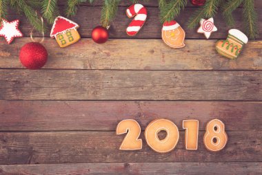 Noel ağacı süslemeleri ve 2018 numaraya benzeyen renkli zencefilli kurabiyeli köknar dalları.