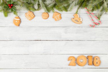 2018 numaralı zencefilli kurabiye tablosu. İçinde birkaç köknar dalı, kozalak ve Noel ağacı süslemeleri var.