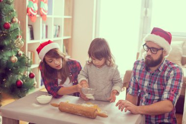 Güzel, genç bir aile Noel kurabiyesi pişirirken eğleniyor. Bebeğe odaklan.