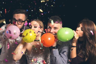 Yılbaşı partisinde dört genç arkadaş geceyarısı renkli balonlar şişirip eğleniyorlar.