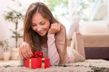 Güzel esmer kız, dairesinin zemininde yatıyordu. Hediyesini alacağı için heyecanlıydı. Açmaya hazırlanıyordu.