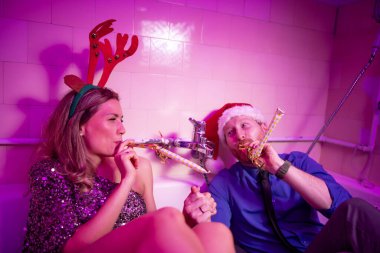 Neşeli genç çift yeni yıl partisinde eğleniyor, küvette oturup gece yarısı için düdük çalıyorlar.