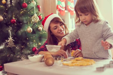 Genç anne ve kız Noel kurabiyeleri pişiriyor ve eğleniyorlar.