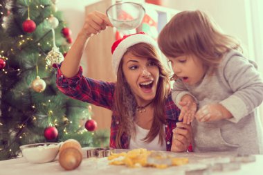 Anne ve kızı Noel kurabiyesi yapıyor ve eğleniyorlar. Annem unu süzgeçten geçirir.