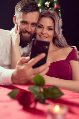 Çekici genç bir çift romantik bir akşam yemeği yerken selfie çekiyor. Adama odaklan.