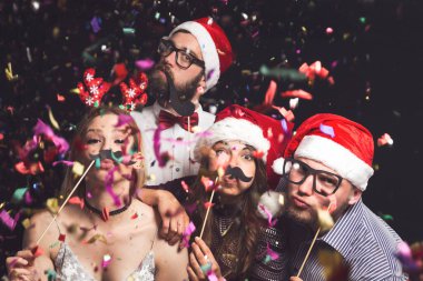 Yılbaşı partisinde maskeli fotoğraflara poz veren dört genç arkadaş.