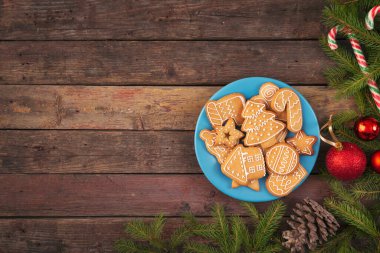 Bir tabakta güzel dekore edilmiş Noel kurabiyeleri tabağı üzerinde çam kozalakları ve Noel süslemeleri var.