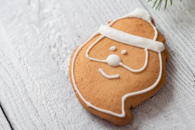Noel Baba şeklinde, beyaz ahşap arka planda beyaz kremalı yüksek açılı Noel kurabiyesi. Seçici odak