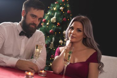 Genç ve çekici bir çift romantik bir Noel yemeği yiyor, şampanya içiyor ve kadeh kaldırıyor..