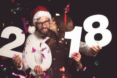 Genç çift yeni yıl partisinde eğleniyor, ellerinde 2018 numaralı karton kutular var.