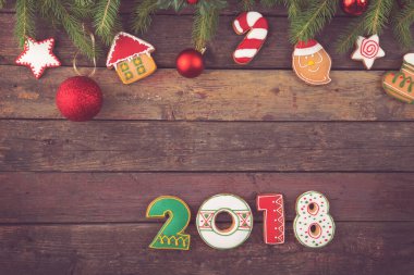Noel ağacı süslemeleri ve 2018 numaraya benzeyen renkli zencefilli kurabiyeli köknar dalları.