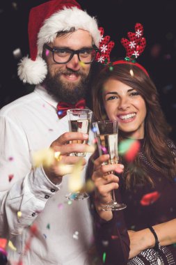 Genç ve güzel bir çift bir partide eğleniyor, ellerinde şampanya bardakları ve kadeh kaldırıyorlar.