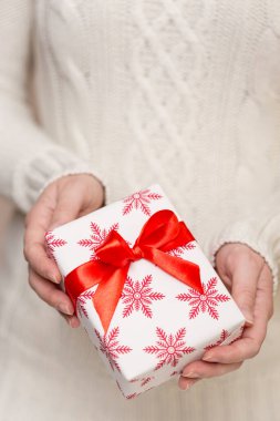 Güzel paketlenmiş hediye kutusunu tutan genç bir kadının detayları.