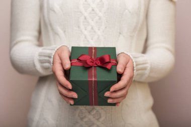 Güzel paketlenmiş hediye kutusunu tutan genç bir kadının elleri. Ellere ve güncel kutuya odaklan