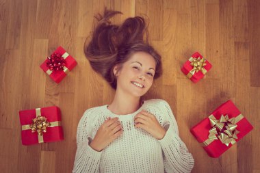 Top view of a young woman lying on the floor surrounded with nicely wrapped presents clipart