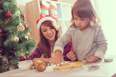 Genç anne ve kız Noel kurabiyeleri pişiriyor ve eğleniyorlar.