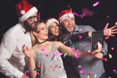 Bir grup genç arkadaş yeni yıl partisinde eğleniyorlar ve çılgın suratlar yapıp selfie çekiyorlar.