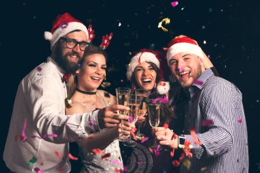 Yılbaşı partisinde kadeh kaldıran bir grup genç arkadaş gece yarısı şampanya kadehleri kaldırıyor.