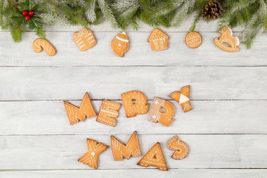 Güzel dekore edilmiş zencefilli Noel kurabiyelerinin üst manzarası. Çam dalları, şeker kamışı ve beyaz ahşap arka planda ökseotu olan mutlu Xmas şekilli.