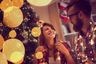 Noel ağacı süsleme, Noel ışıkları düzenlenmesi ve having fun aşık güzel genç Çift