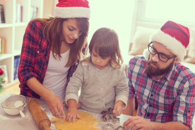 Güzel, genç bir aile Noel kurabiyesi pişirirken eğleniyor. Anneye ve bebeğe odaklan.