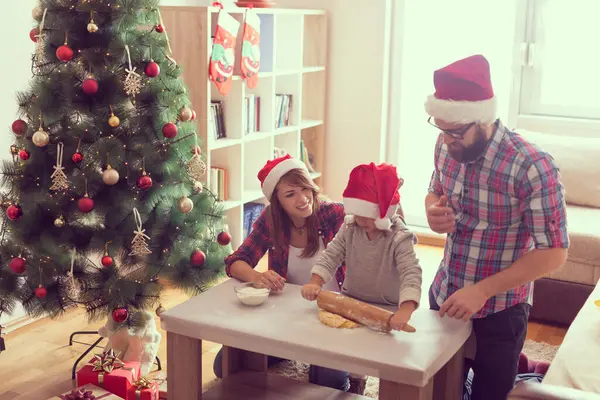 Güzel, genç bir aile Noel kurabiyesi pişirirken eğleniyor. Annesine odaklan.