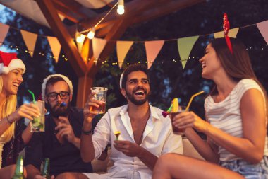 Bir grup genç arkadaş parti düdüğü çalıyor, bira içiyor, kadeh kaldırıyor ve dışarıda yeni yıl partisinde eğleniyorlar.