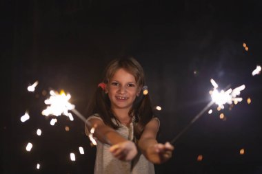 Noel arifesinde maytap tutarken ve el sallarken eğlenen güzel küçük bir kızın portresi.
