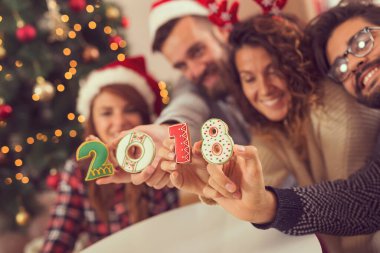 2018 numaralı Noel kurabiyeleri taşıyan dört genç arkadaş Noel günü eğleniyorlar. Bir numara şeklindeki kurabiyeye odaklan.