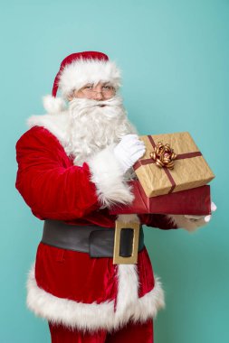 Noel Baba 'nın portresi, güzelce paketlenmiş hediye kutularını tutuyor ve içine bakıyor. Renkli arka planda izole bir şekilde.