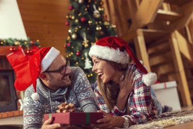 Güzel, birbirine aşık genç bir çift yerde şömine ve Noel ağacının yanında yatıyor, Noel sabahı hediyelerini değiş tokuş ediyorlar.