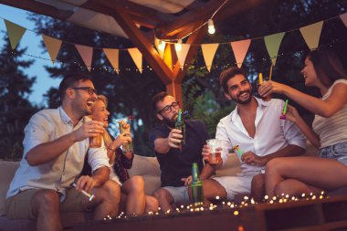 Bir grup genç arkadaş parti düdüğü çalıyor, bira içiyor ve açık hava yaz partisinde eğleniyorlar.