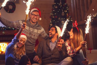 Bir grup genç arkadaş yılbaşı kutlamasında eğleniyorlar, gece yarısı geri sayımında maytap tutuyorlar. Erkeklere odaklan.