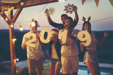 Bir grup genç arkadaş yeni yıl havuz partisinde eğleniyor, dans ediyor, karton kar taneleri tutuyor ve 2019 numara