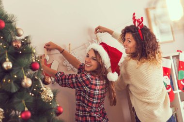 Noel için evi dekore eden iki güzel genç kadın. Soldaki kıza odaklan.