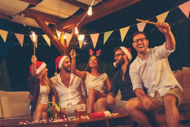 Arkadaşlar dışarıda yeni yıl partisinde eğleniyor, dans ediyor, bira içiyor, kokteyl içiyor ve gece yarısı havai fişeklerle el sallıyor.