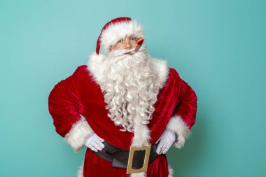 Noel Baba parti düdüğü çalıyor, yeni yılı kutluyor ve eğleniyor. Renkli arka planda izole edilmiş.