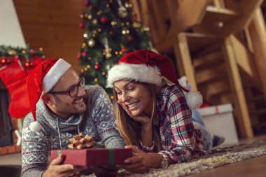 Güzel, birbirine aşık genç bir çift yerde şömine ve Noel ağacının yanında yatıyor, Noel sabahı hediyelerini değiş tokuş ediyorlar.
