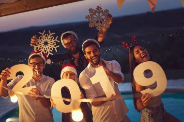 Bir grup genç arkadaş yeni yıl havuz partisinde eğleniyor, dans ediyor, karton kar taneleri tutuyor ve 2019 numara