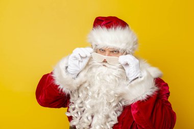 Noel Baba parti gözlüğü takıyor. Kış tatilinde eğleniyor. Sarı arka planda izole edilmiş.