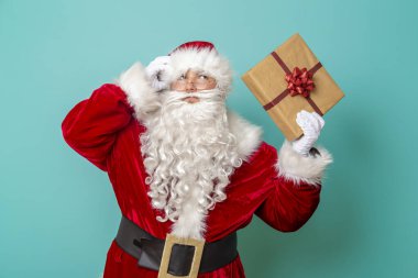 Noel Baba 'nın portresi güzelce paketlenmiş Noel hediyesini tutuyor ve sallıyor. Renkli arka planda izole edilmiş.