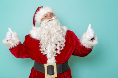 Dans eden Noel Baba 'nın portresi. Nane rengi arka planda izole edilmiş baş parmaklarını gösteriyor.