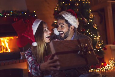 Genç aşık çift şöminenin yanında oturuyor ve Noel ağacını süslüyor, hediyeleri açıyor ve Noel arifesinde eğleniyorlar.