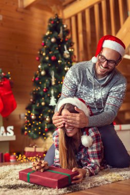 Aşık bir çift yerde şömine ve Noel ağacının yanında yatıyor, Noel sabahı hediye alışverişi yapıyor, kadın tutan bir adam gözlerini kapatıyor. Kıza odaklan.