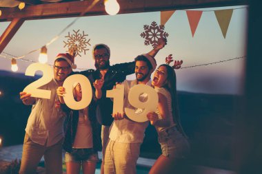 Bir grup genç arkadaş yeni yıl havuz partisinde eğleniyor, dans ediyor, karton kar taneleri tutuyor ve 2019 numara