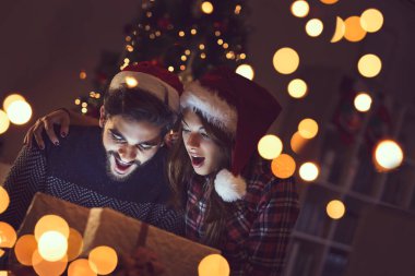 Birbirine aşık genç bir çift Noel ağacının yanında oturuyor, hediyeleri açıyor ve eğleniyorlar. Kıza odaklan.