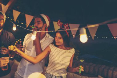 Bir grup genç arkadaş yeni yıl havuz partisinde eğleniyor, dans ediyor, parti düdüğü çalıyor ve kokteyl içiyor.