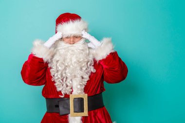 Noel Baba 'nın el ele tutuşması, baş ağrısı, nane rengi arka planda izole edilmesi, Noel Baba' nın kış tatilinde grip olması.